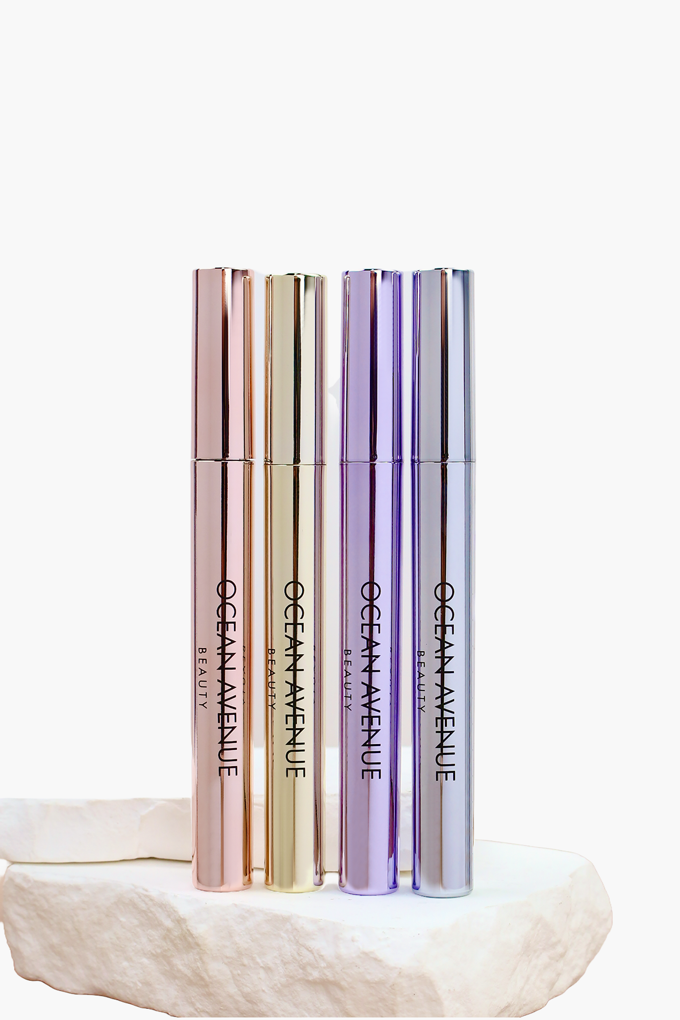 Ocean Avenue Beauty peel-off lip stain collection—four metallic tubes on stone pedestal.