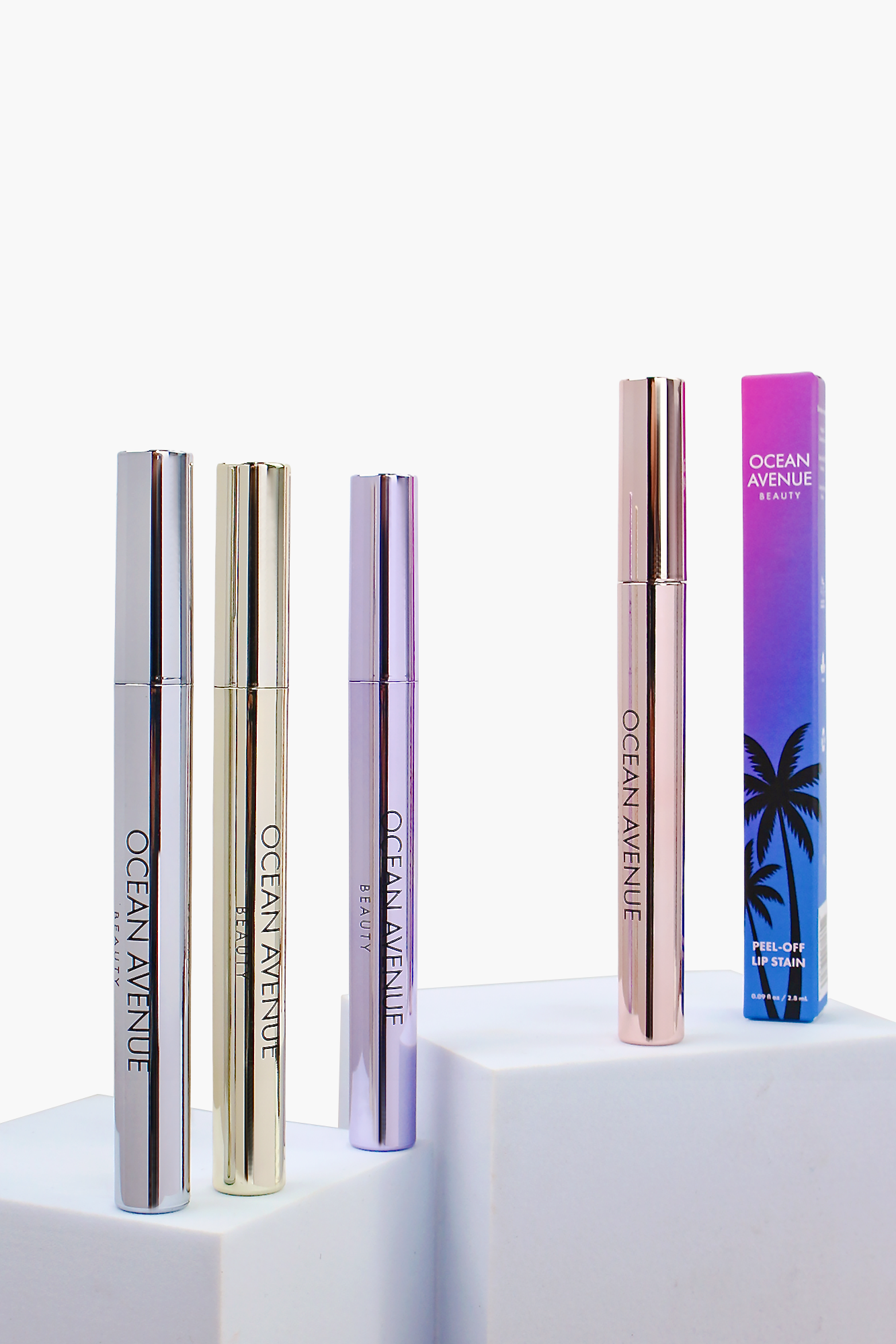 Ocean Avenue Beauty peel-off lip stain collection—four tubes and box on white pedestals.
