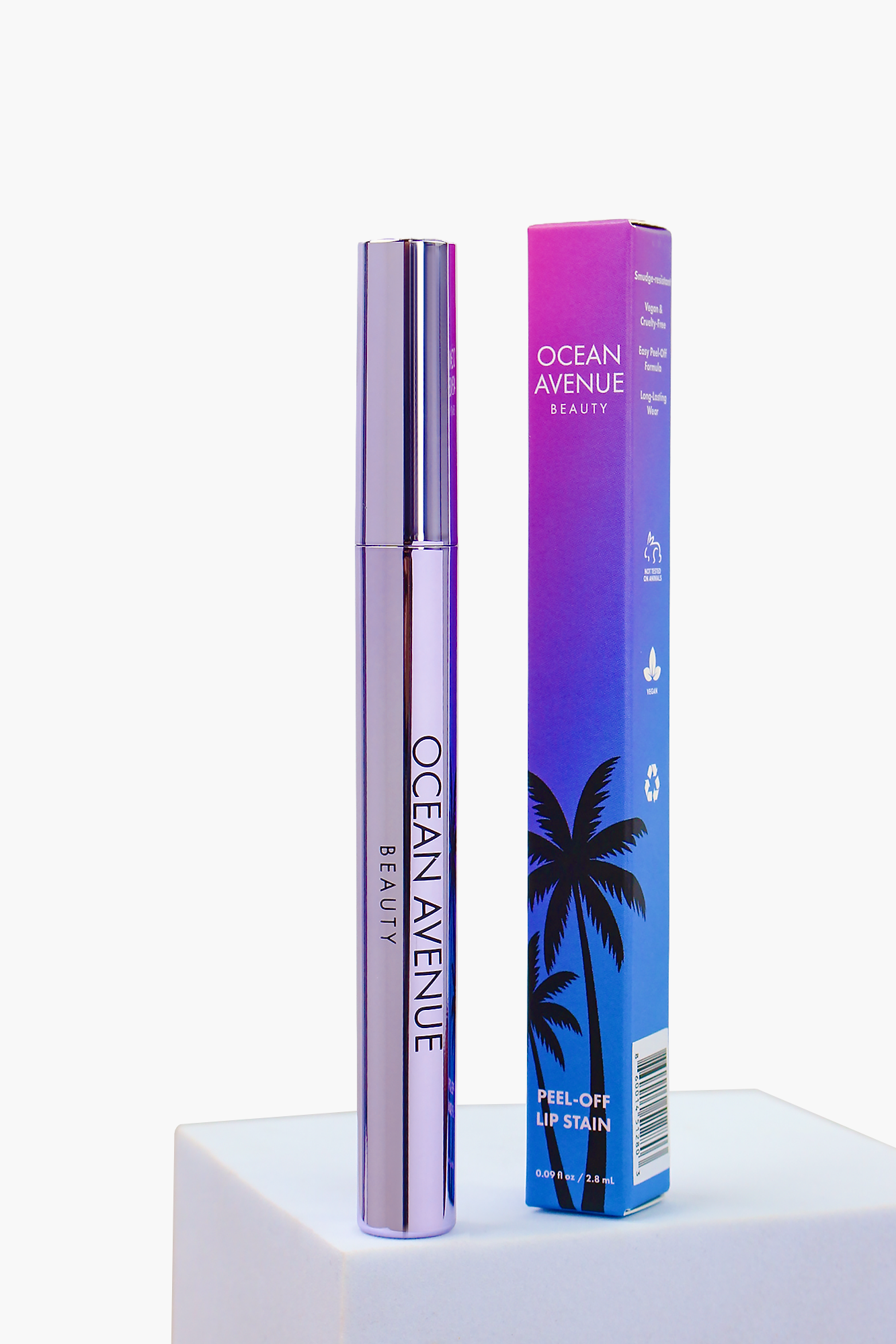 Midnight Palms peel-off lip stain—tube and retail box on a pedestal, Ocean Avenue Beauty.